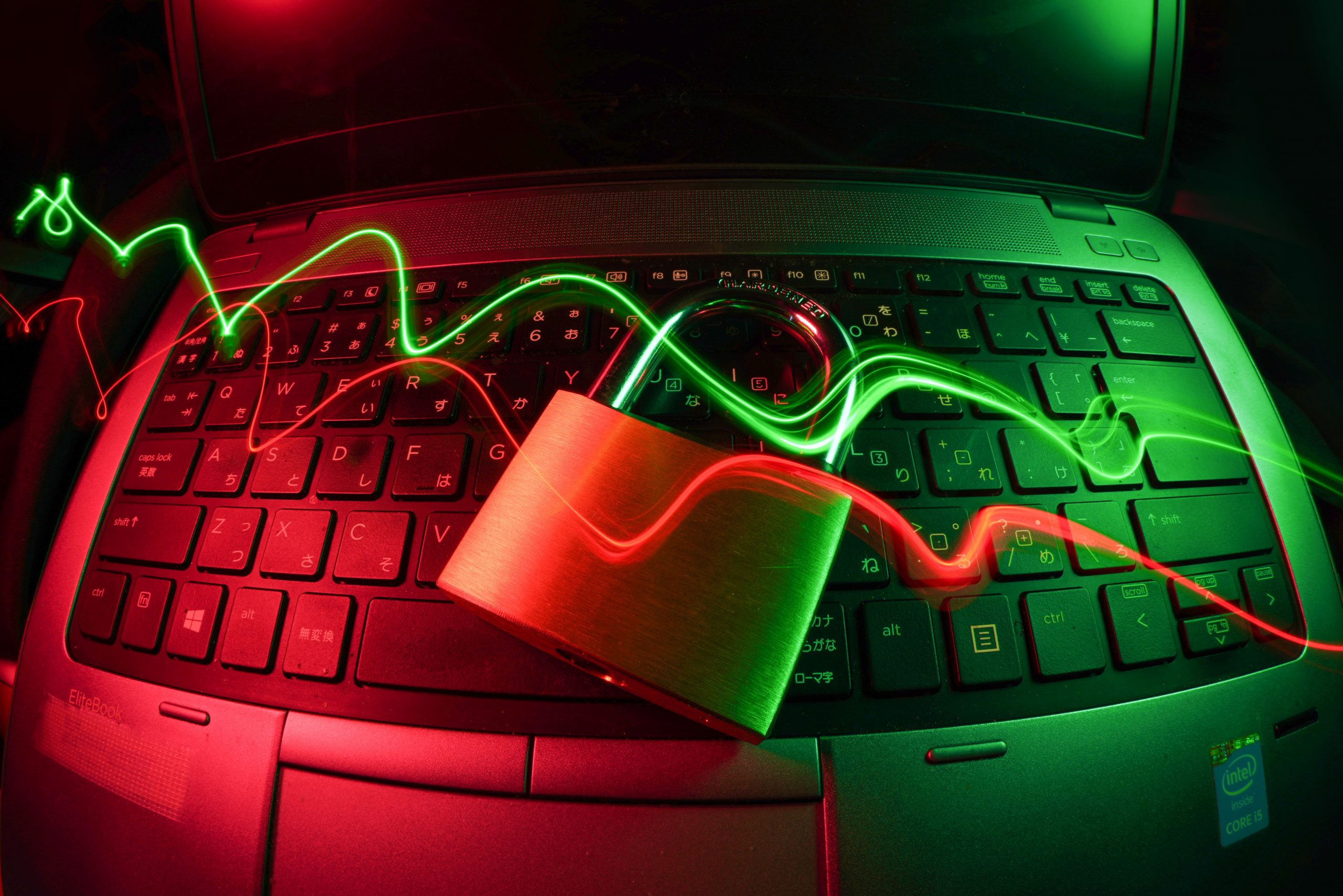 a padlock in front of a computer with graphic laser waves on top of it